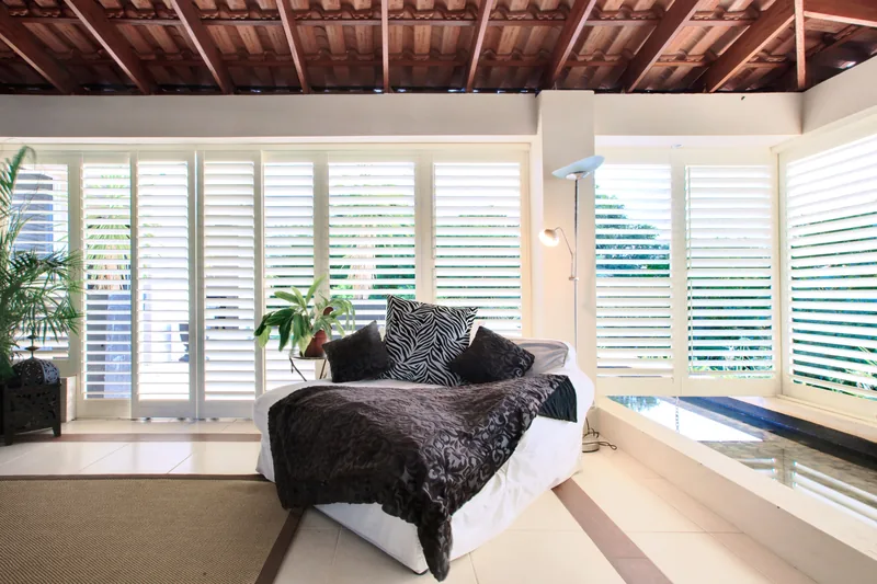 White powder-coated aluminium shutters on a poolside patio